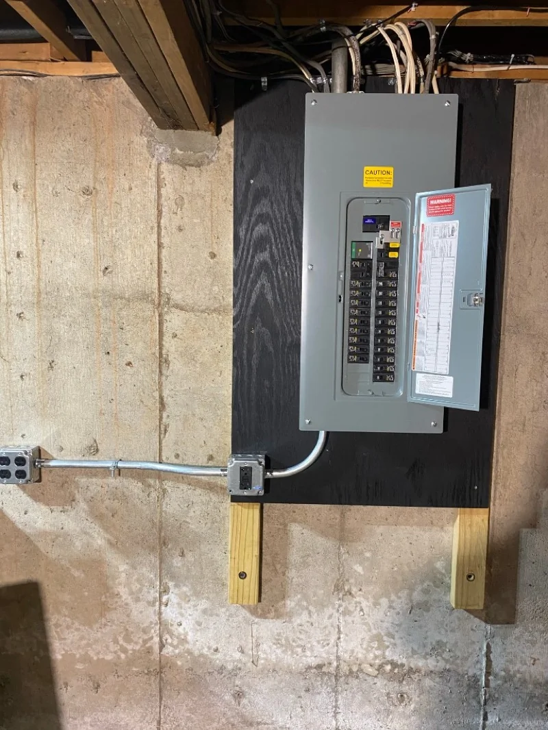 Residential circuit breaker panel installation on a basement wall with conduit and home electrical service wiring in Connecticut